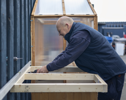 A man is building a small green house. 