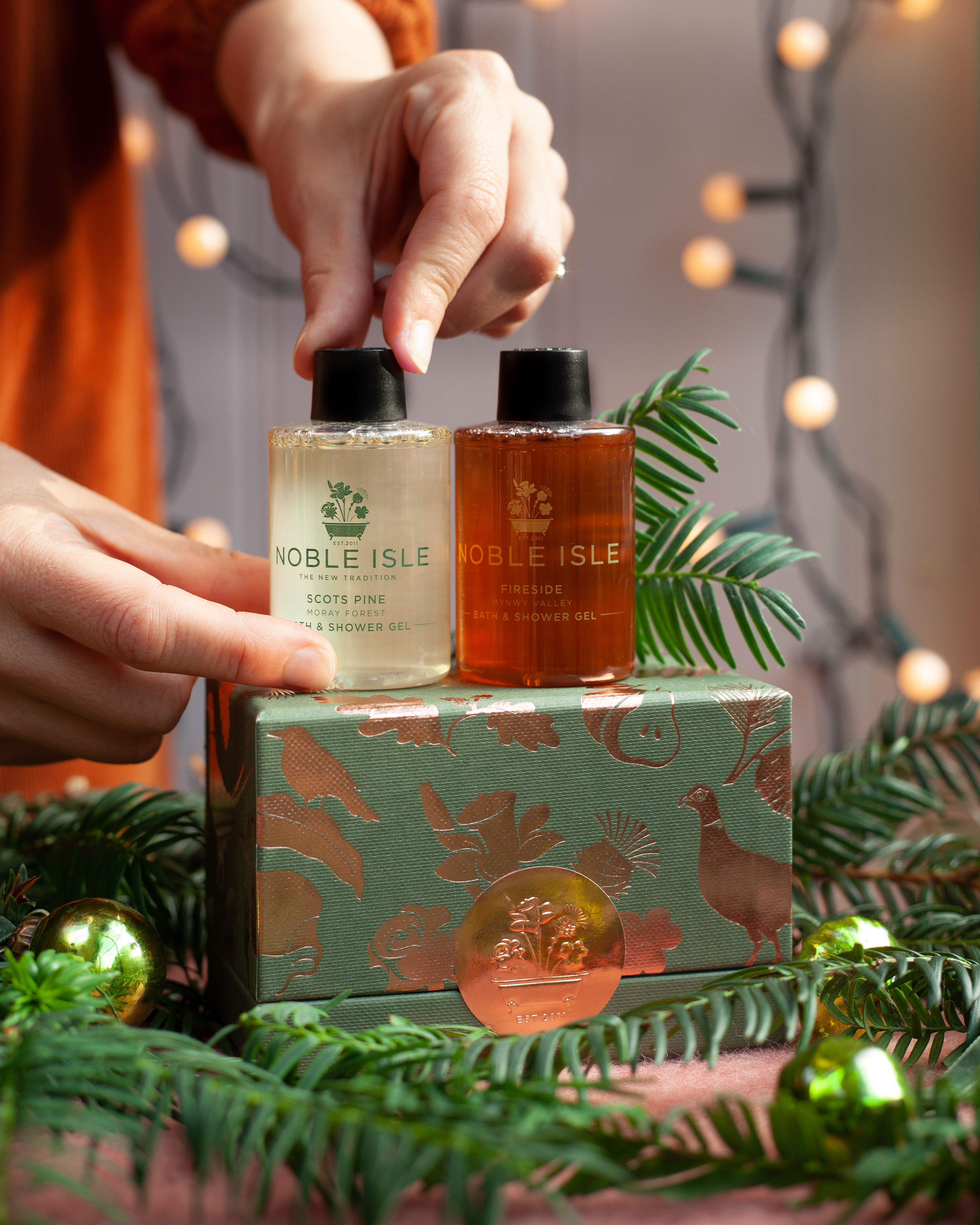 Noble Isle shower gels displayed on top of a gold and green box