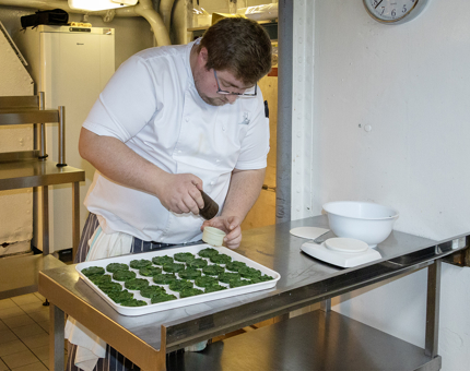 A Chef preparing spinach dishes in the onboard Galley. 