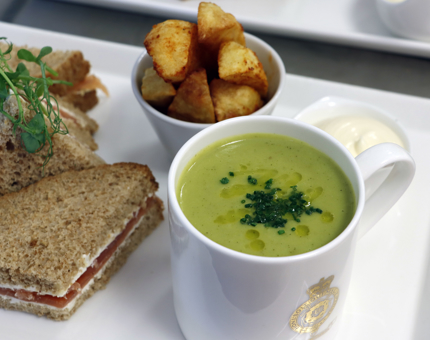 A platter containing a sandwich, potato wedges and a mug of soup. 