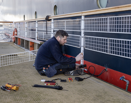 A member of the Maintenance Team is disconnecting the electricity while sitting on a pontoon. 
