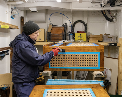 A member of the Maintenance team varnishing a wooden rope box. 