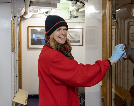 A Housekeeper polishing glass in a corridor onboard the Yacht.