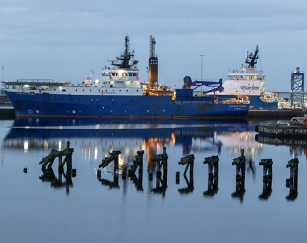 Two large ships in the harbour at dusk. 