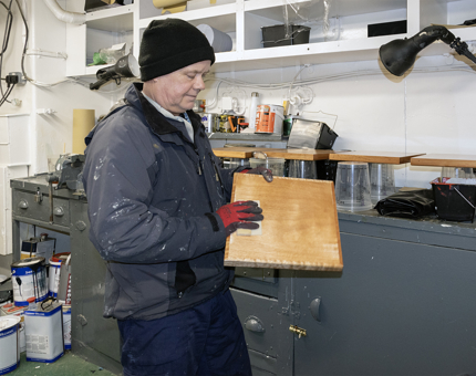 Man in blue jacket holding a piece of wood 