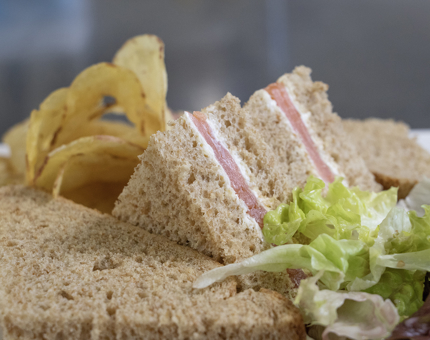 Smoked salmon and cream cheese sandwiches with salad and crisps on a plate. 
