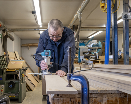A member of the Maintenance team making wooden drawer units in the workshop.