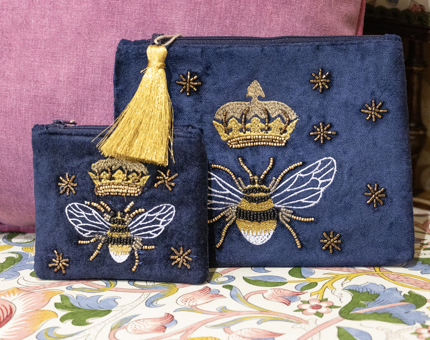Two navy blue embroidered velvet zip purses with decorative bee designs. 