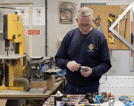 A member of the Maintenance Team working on a door keypad in the workshop. 