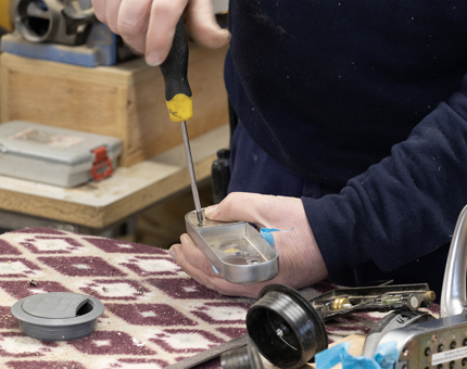 A detailed look as the man uses a screwdriver to disconnect the keypad. 