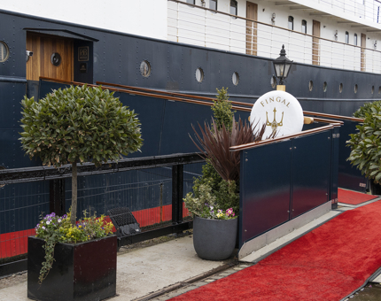 The outside and brow of Fingal. There is a red carpet and pots filled with plants and shrubs. 
