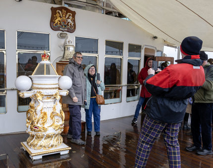 A couple pose for photo next to the Bell on the Verandah Deck. 