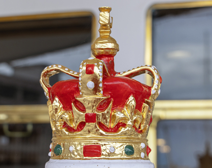 A red and gold crown on top of the compass binnacle. 