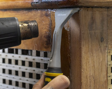 A close-up of the heat gun removing the varnish. 