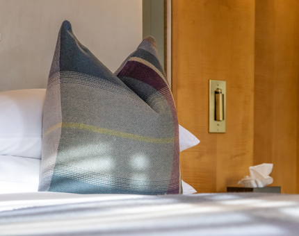 A tartan-covered pillow on a bed in a Fingal cabin. 