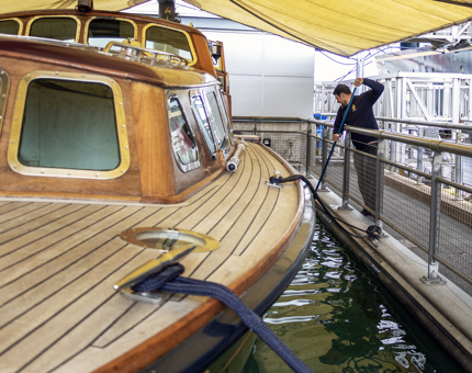 A member of the Maintenance team cleaning the pond where the Royal Barge is displayed.