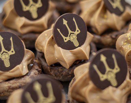 A tray of chocolate sweet delicacies from Fingal's Afternoon Tea menu. Chocolate discs decorated with the Fingal trident are on top. 