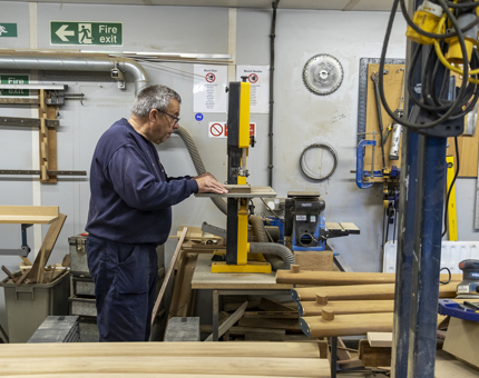 A man in a workshop cutting wood. 