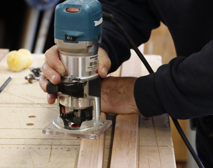 A close-up of a man cutting wood to make a picture frame. 