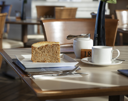 A piece of carrot cake with a cup of tea on a table.