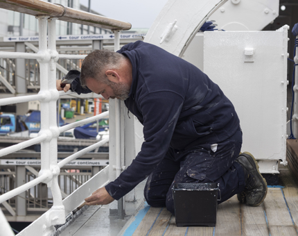 A man painting a handrailing white. 