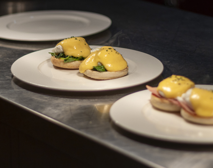 Two plates, one with eggs benedict and one with eggs Florentine. 