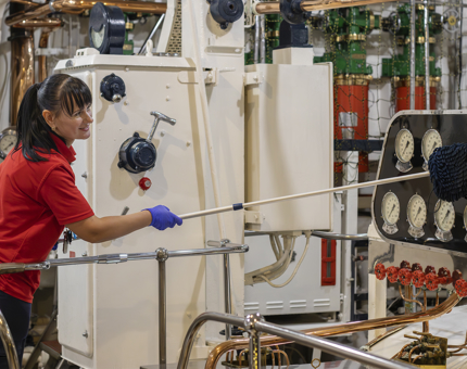 A woman in a red shirt cleaning the Engine Room. 