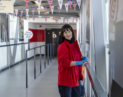A Housekeeper dusting handrails on Britannia.