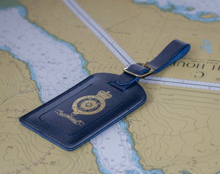 A blue luggage tag with a gold Britannia crest. 