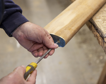 A hand holding a screwdriver attaching brass to the end of a handrail. 
