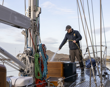 A man is washing down Royal Racing Yacht Bloodhound. 
