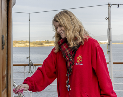 A Housekeeper polishing a brass handrail on the Verandah Deck. 
