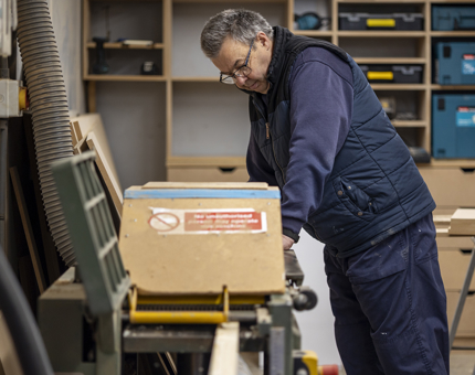 A Maintenance team member cutting wood in the workshop. 