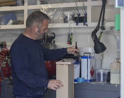 A man varnishing a drawer. 