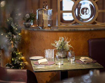 Dinner tables set in The Lighthouse Restaurant & Bar with Christmas foliage decorating them. 