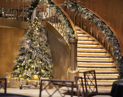 Fingal Hotel's Ballroom staircase, there are Christmas garlands on the hand rails, and a Christmas tree at the bottom of the stairs. 