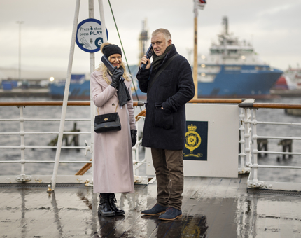 Two visitors listening to the audio guide handset on the Verandah Deck of Britannia.