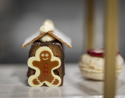 A gingerbread house cake with a gingerbread man on the front. 