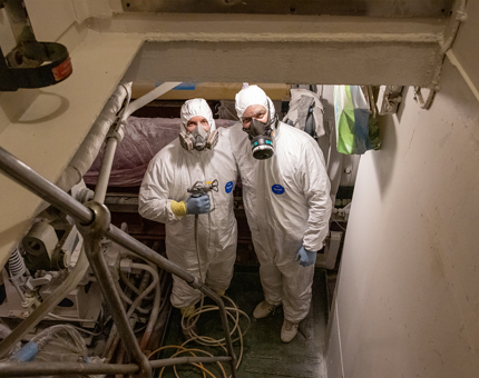 Two Maintenance team members wearing white coveralls. 