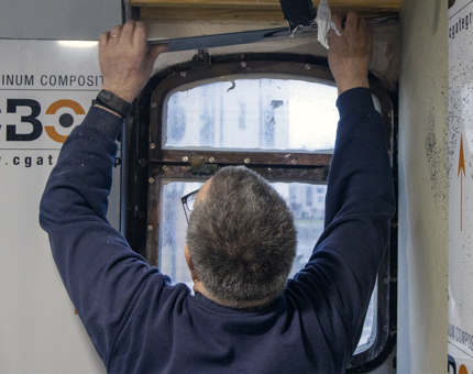 A man paneling a window aboard Fingal Hotel. 