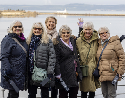 A group of six ladies pose for a photo on the deck of The Royal Yacht Britannia. 