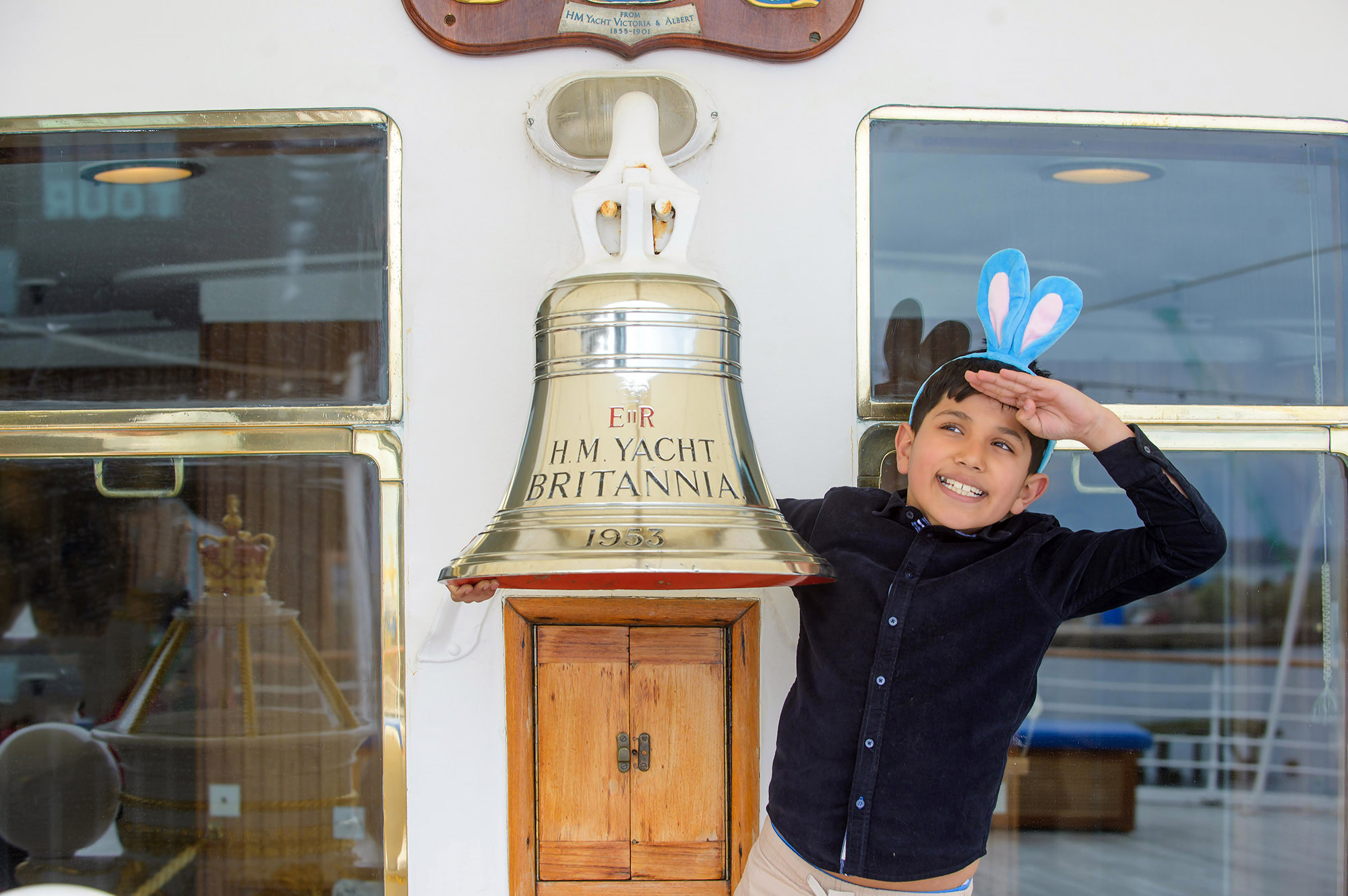 A boy wearing blue bunny ears next to the Britannia Bell. 