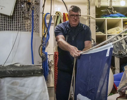 A maintenance man is sorting out dress flags. 