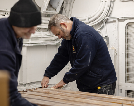 Two Maintenance men sanding handrails. 