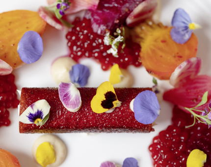 A close up of the heritage beetroot salad from The Lighthouse Restaurant, it is vibrant with reds and orange colours, as well as small flowers. 