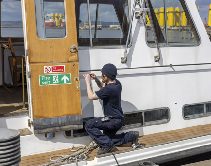 A Maintenance team member is screwing in a door plate on Royal Nore in Leith. 