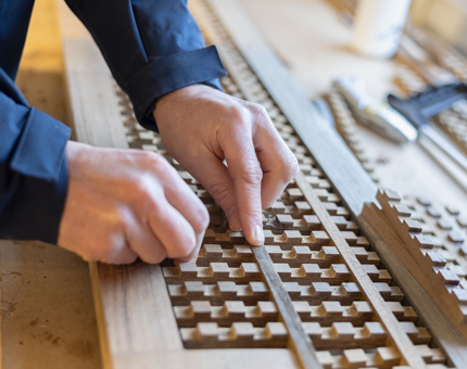 A close up of hands adding wooden blocks to a scupper board. 