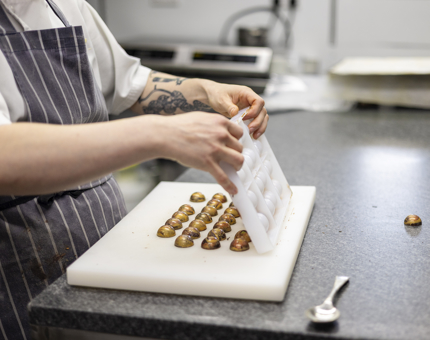 A chef in Britannia's Galley is taking whisky and orange chocolates out of their mold. 