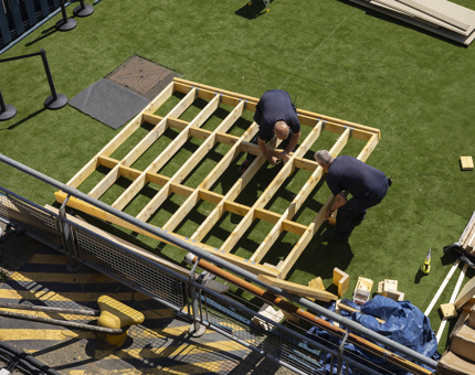 An aerial view of two workmen making a wooden frame at Britannia in Leith. 