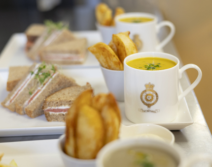 In the Galley, a line of Britannia platters are ready to be served. They have a mug of soup, a sandwich and potato wedges. 
